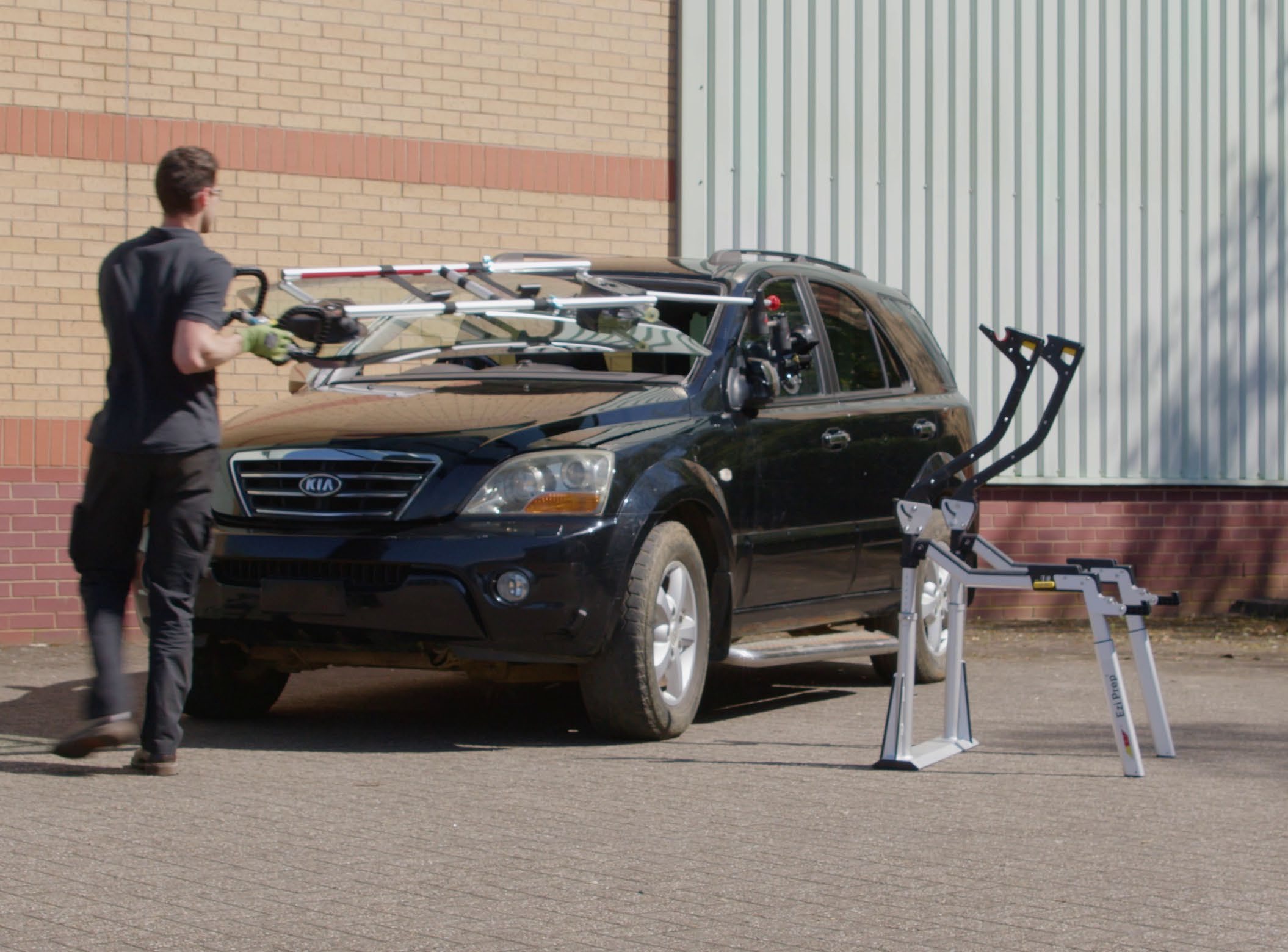 A technician positions a windscreen over a vehicle using the Ezi-Prep brace