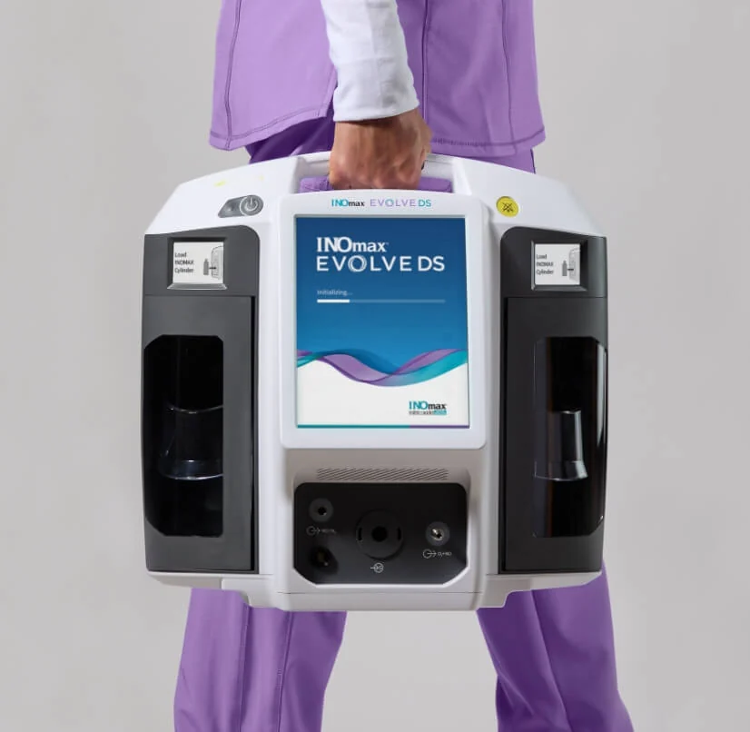 A clinician carrying the portable INOmax EVOLVE DS using its top handle